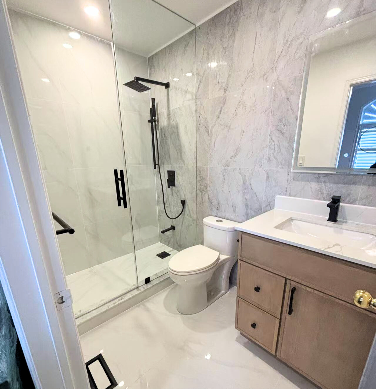 Mississauga 3382 bathroom renovation project featuring round LED mirror and dark textured tiles